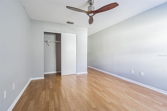 unfurnished bedroom with light wood-style floors, a closet, a textured ceiling, and visible vents