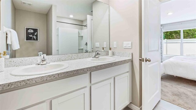 full bath featuring a sink, double vanity, a shower, and visible vents