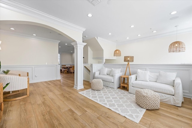 1476 Harbour Walk Rd, Tampa, FL 33602 - living area featuring crown molding, ornate columns, a decorative wall, a wainscoted wall, and light wood-style floors