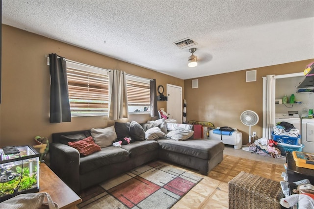 living room featuring a textured ceiling, visible vents, and washer and clothes dryer