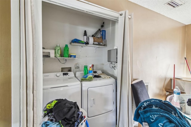 washroom with washing machine and clothes dryer, a textured ceiling, laundry area, and visible vents