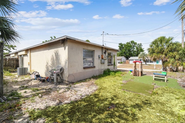 back of house featuring central AC, fence, and stucco siding