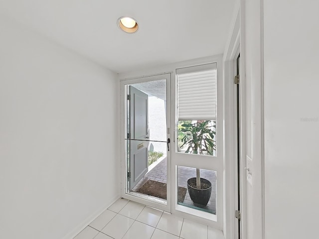 doorway to outside featuring baseboards and light tile patterned flooring