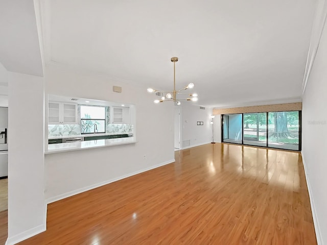 spare room with baseboards, ornamental molding, wood finished floors, and a notable chandelier