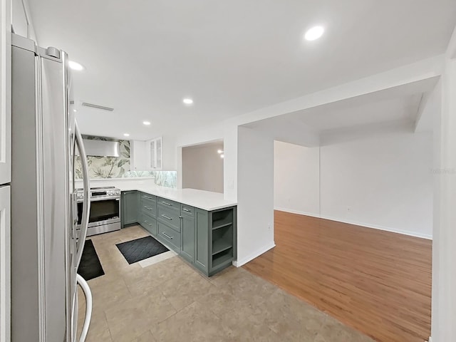 kitchen featuring open shelves, recessed lighting, light countertops, wall chimney exhaust hood, and appliances with stainless steel finishes