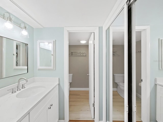 full bath featuring vanity, baseboards, wood finished floors, and toilet