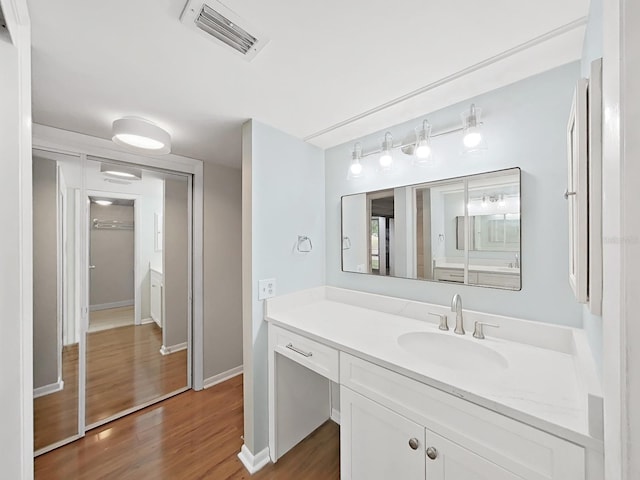 bathroom with baseboards, visible vents, wood finished floors, and vanity