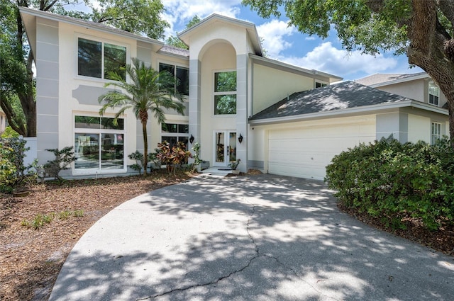 view of front of property featuring french doors, stucco siding, an attached garage, and driveway