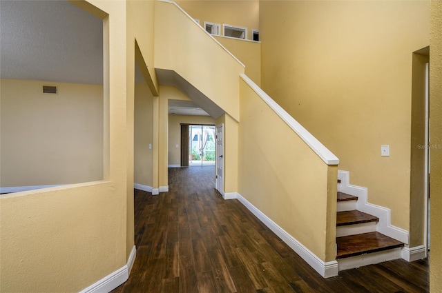 hall with stairway, baseboards, dark wood-type flooring, and visible vents