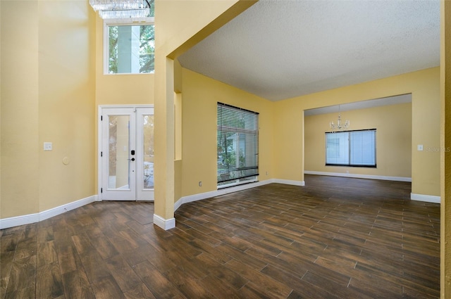 entryway with a chandelier, a wealth of natural light, and dark wood finished floors