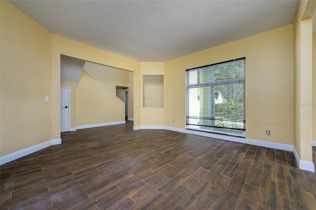 spare room with dark wood-style flooring, baseboards, and a textured ceiling