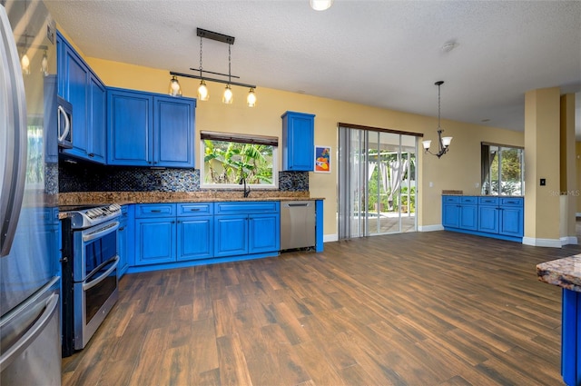 kitchen featuring blue cabinetry, a chandelier, a textured ceiling, stainless steel appliances, and backsplash