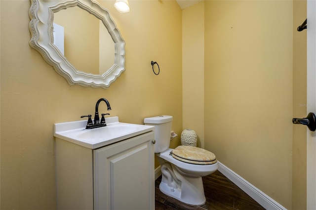 bathroom with toilet, baseboards, wood finished floors, and vanity