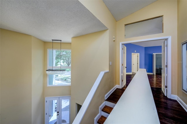 hall with baseboards, french doors, dark wood-style floors, and a textured ceiling