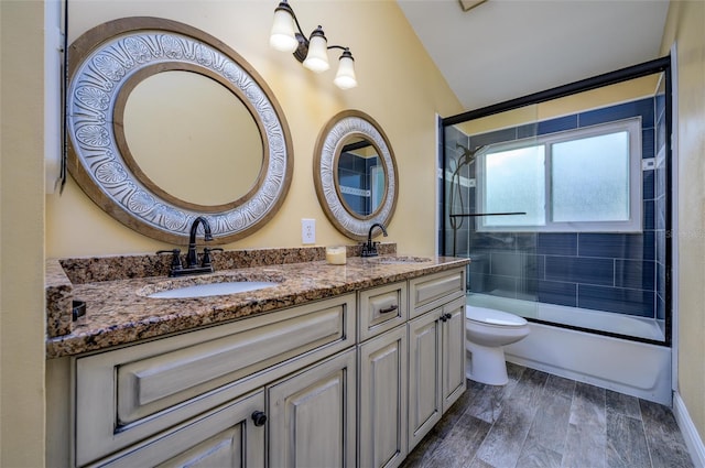 bathroom with double vanity, toilet, vaulted ceiling, and a sink