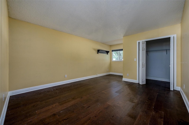 unfurnished bedroom featuring a textured ceiling, baseboards, dark wood finished floors, and a closet