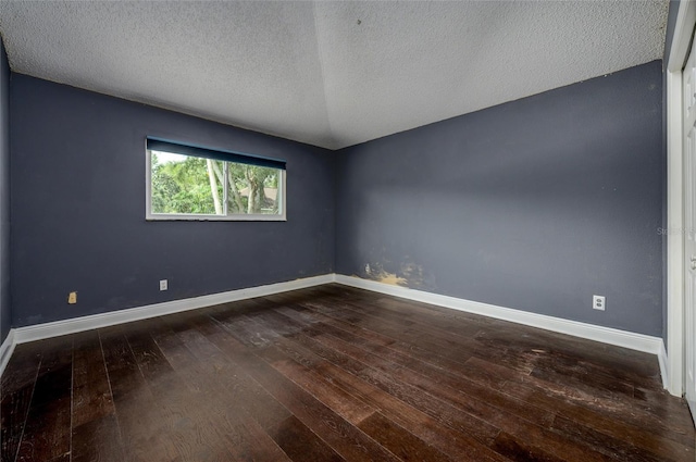 empty room featuring dark wood-type flooring, a textured ceiling, and baseboards