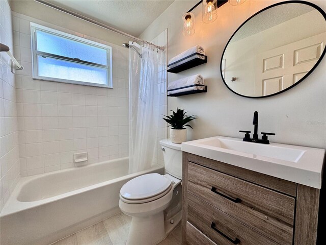 bathroom with vanity, shower / bathtub combination with curtain, toilet, and a textured ceiling
