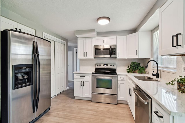 4940 Rosedale Ln, Holiday, FL 34690 - kitchen featuring light stone countertops, a sink, light wood-style flooring, stainless steel appliances, and white cabinetry