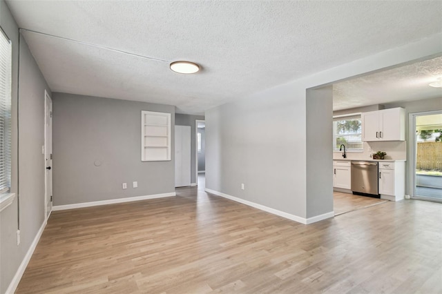 4940 Rosedale Ln, Holiday, FL 34690 - unfurnished living room featuring baseboards, a sink, a textured ceiling, and light wood finished floors