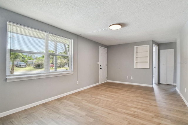 4940 Rosedale Ln, Holiday, FL 34690 - empty room with light wood-style floors, a textured ceiling, and a wealth of natural light