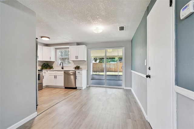 4940 Rosedale Ln, Holiday, FL 34690 - kitchen featuring visible vents, stainless steel dishwasher, light countertops, white cabinets, and light wood-style floors