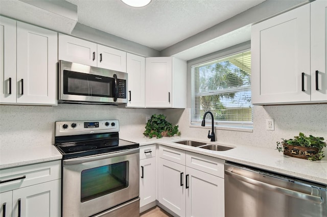 4940 Rosedale Ln, Holiday, FL 34690 - kitchen featuring white cabinets, appliances with stainless steel finishes, light stone counters, a sink, and a textured ceiling