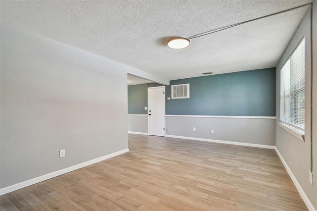 4940 Rosedale Ln, Holiday, FL 34690 - empty room with a textured ceiling, visible vents, baseboards, and light wood-style floors