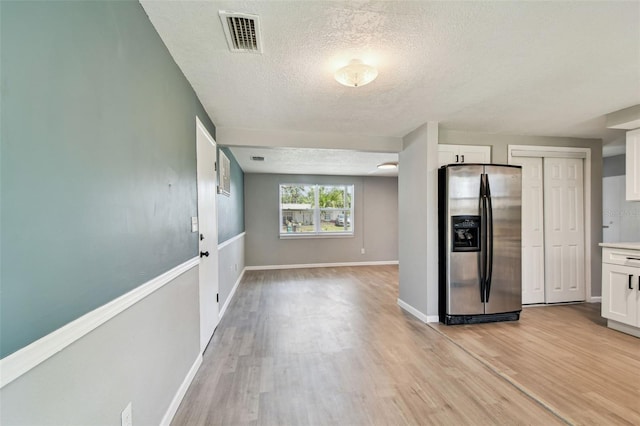 4940 Rosedale Ln, Holiday, FL 34690 - kitchen with a textured ceiling, visible vents, light wood finished floors, and stainless steel fridge with ice dispenser