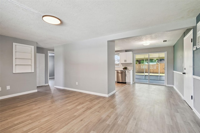 4940 Rosedale Ln, Holiday, FL 34690 - unfurnished living room featuring light wood-type flooring, a textured ceiling, and visible vents