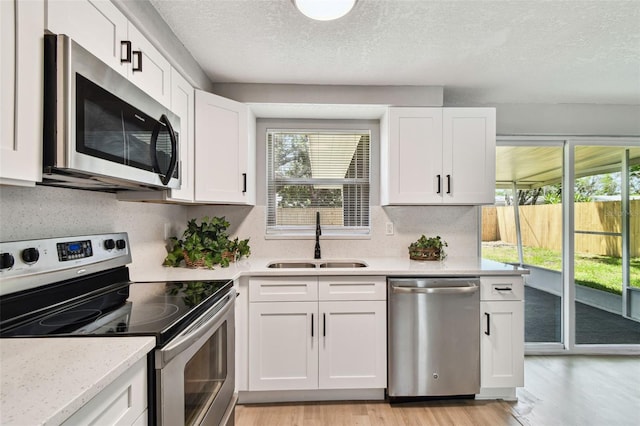 4940 Rosedale Ln, Holiday, FL 34690 - kitchen featuring a sink, appliances with stainless steel finishes, light wood-style flooring, and a healthy amount of sunlight