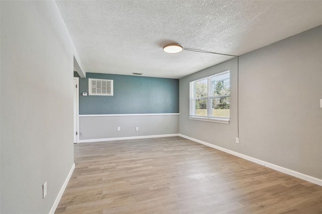 4940 Rosedale Ln, Holiday, FL 34690 - empty room featuring visible vents, a textured ceiling, light wood finished floors, and baseboards