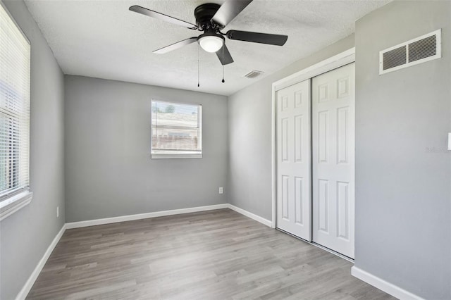 4940 Rosedale Ln, Holiday, FL 34690 - unfurnished bedroom with wood finished floors, a closet, a textured ceiling, and visible vents