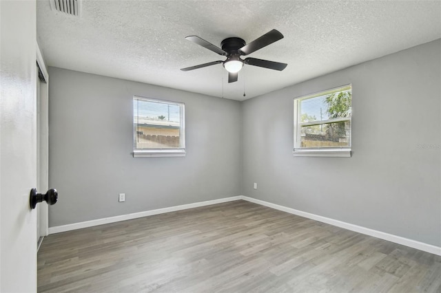 4940 Rosedale Ln, Holiday, FL 34690 - empty room featuring visible vents, a textured ceiling, plenty of natural light, and wood finished floors