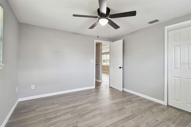 4940 Rosedale Ln, Holiday, FL 34690 - unfurnished bedroom featuring ceiling fan, a textured ceiling, baseboards, wood finished floors, and visible vents