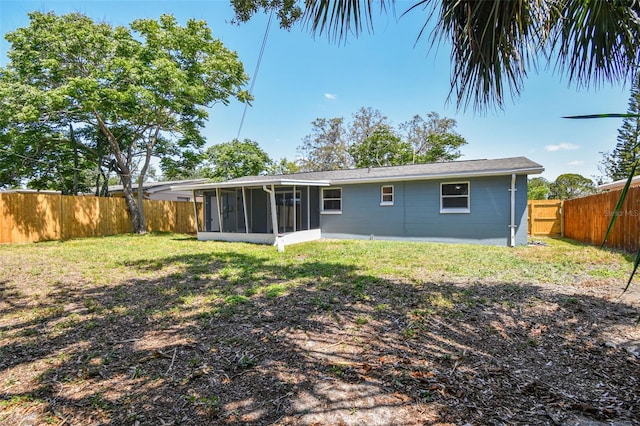 4940 Rosedale Ln, Holiday, FL 34690 - rear view of house with a fenced backyard, a lawn, and a sunroom