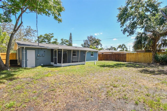 4940 Rosedale Ln, Holiday, FL 34690 - rear view of house featuring a lawn, a fenced backyard, and a sunroom