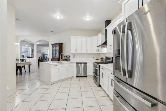 19129 Lake Audubon Dr, Tampa, FL 33647 - kitchen with a sink, arched walkways, wall chimney exhaust hood, stainless steel appliances, and a peninsula