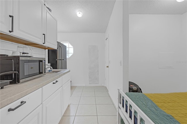 4617 Horseshoe Pick Ln, Valrico, FL 33594 - kitchen featuring stainless steel microwave, a textured ceiling, light countertops, white cabinets, and baseboards