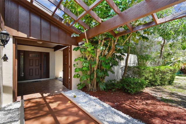 doorway to property featuring a pergola, stucco siding, and board and batten siding