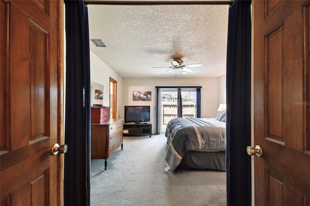 bedroom with a textured ceiling, light carpet, visible vents, and ceiling fan