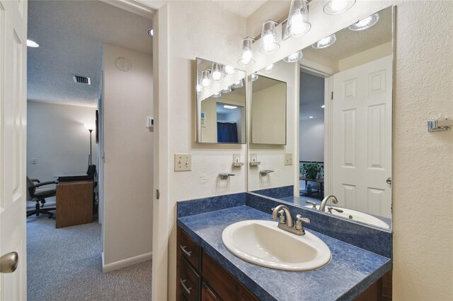 bathroom featuring vanity, a textured ceiling, baseboards, and visible vents