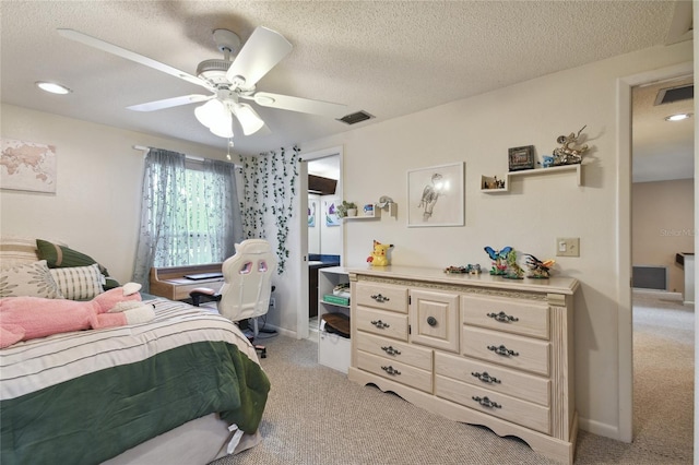 bedroom with light colored carpet, a textured ceiling, visible vents, and a ceiling fan