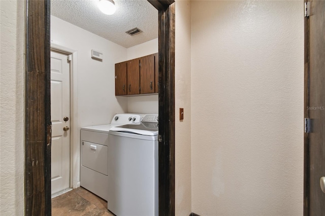 laundry area featuring a textured ceiling, cabinet space, visible vents, and washer and dryer