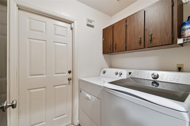 clothes washing area featuring cabinet space, washing machine and dryer, and a textured ceiling