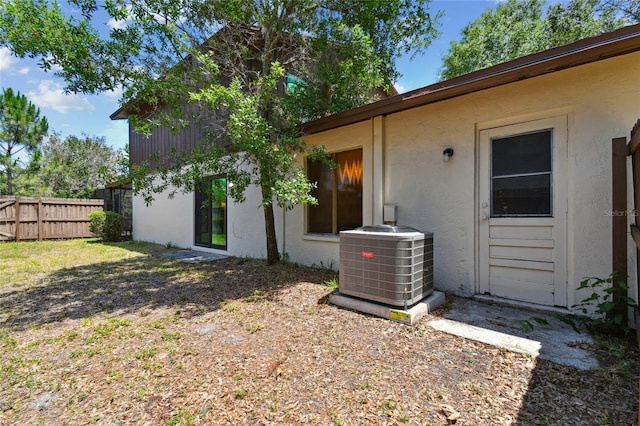 exterior space featuring cooling unit, stucco siding, and fence