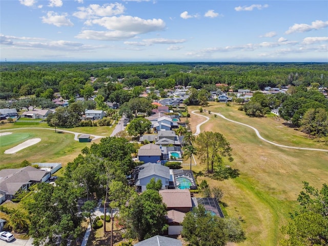 drone / aerial view featuring view of golf course, a forest view, and a residential view