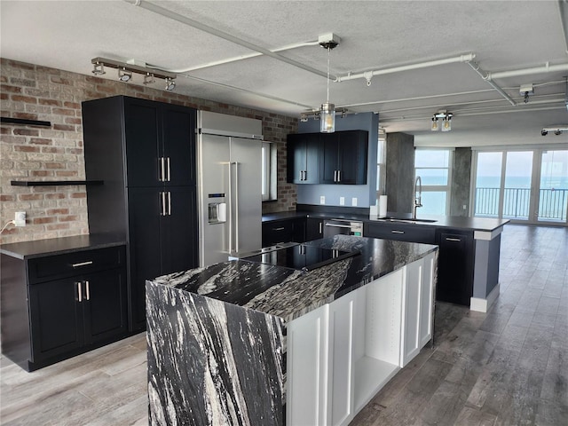 kitchen with a peninsula, dark cabinets, a sink, dark countertops, and stainless steel appliances