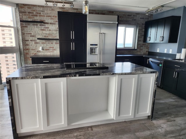 kitchen with rail lighting, dark countertops, stainless steel appliances, and a center island