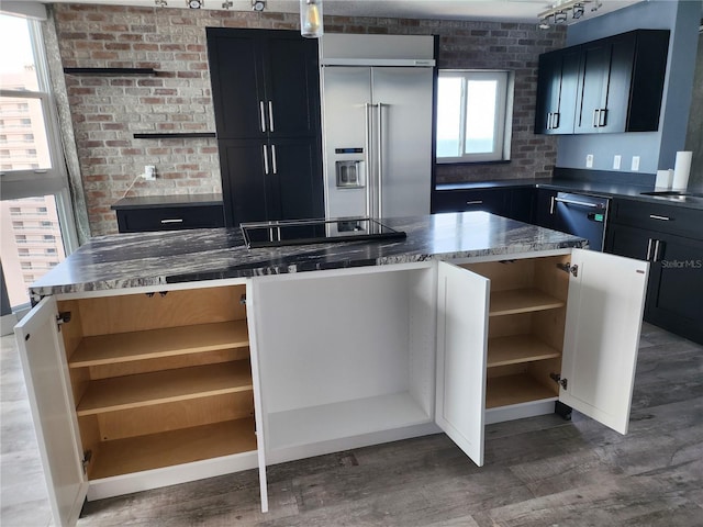 kitchen featuring a center island, dark cabinets, open shelves, wood finished floors, and stainless steel appliances